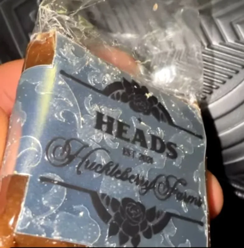 A silver HEADS x Huckleberry Hill Farms wrapper over a slab of hash